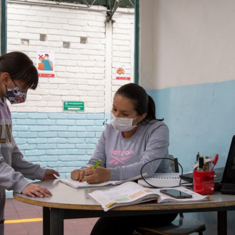 Profesora en clase explicando a estudiante 